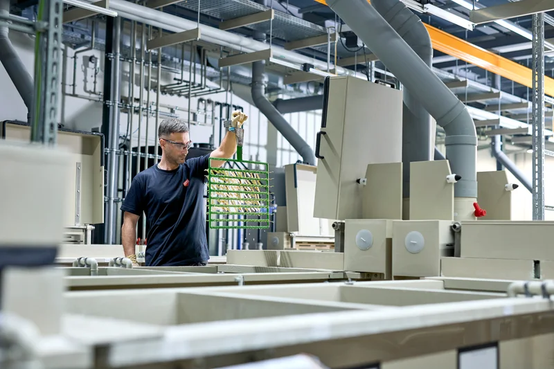 Mitarbeiter der C. Jentner GmbH hebt ein Gestell in der Gestellgalvanik